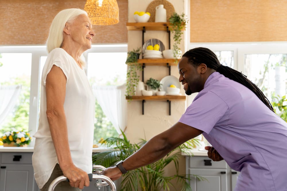 Caregiver helping a client walk with a walker at home