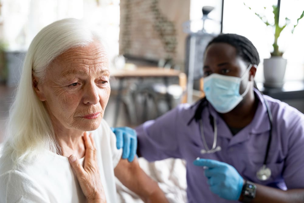Nurse administering an injection to a client at home
