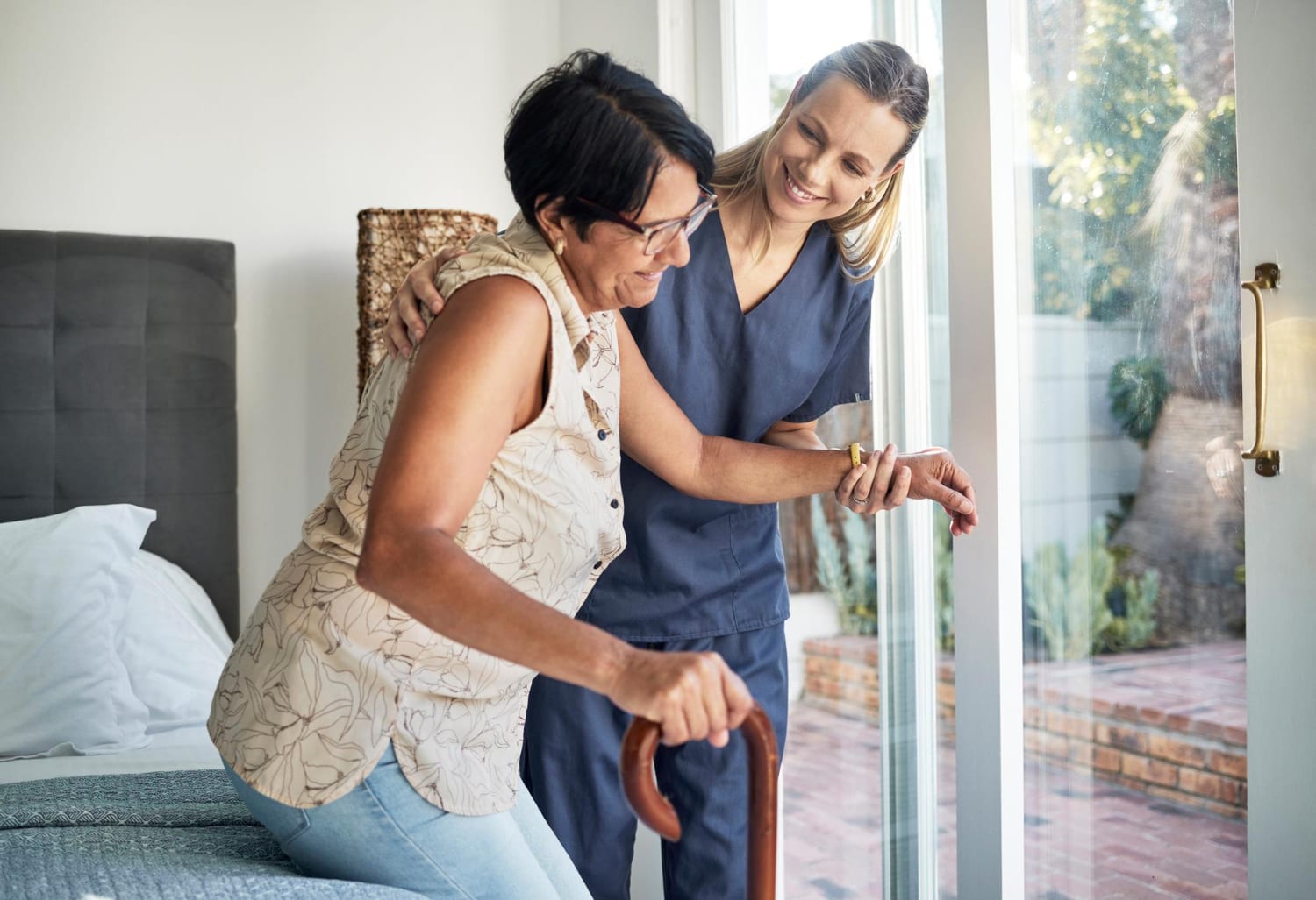Caregiver helping a client walk with a cane at home
